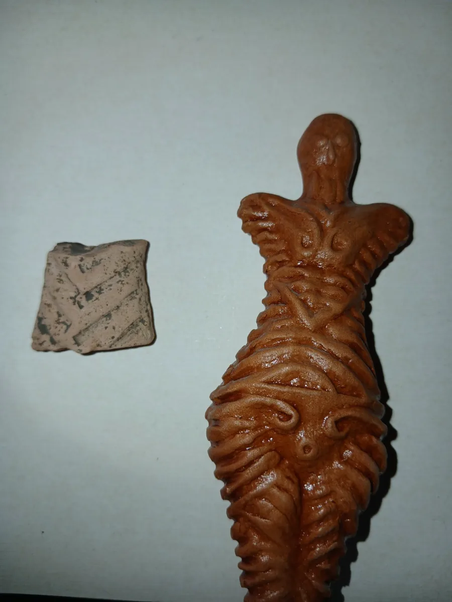 Statuetă de lut de tip Cucuteni, alături de un fragment de ceramică