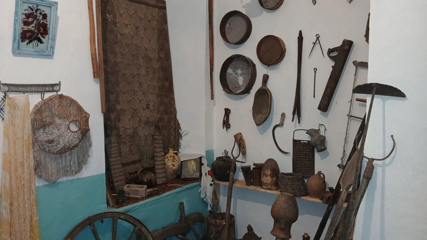 Colț din sala etnografică, cu oale de lut, unelte și o roată de căruță
